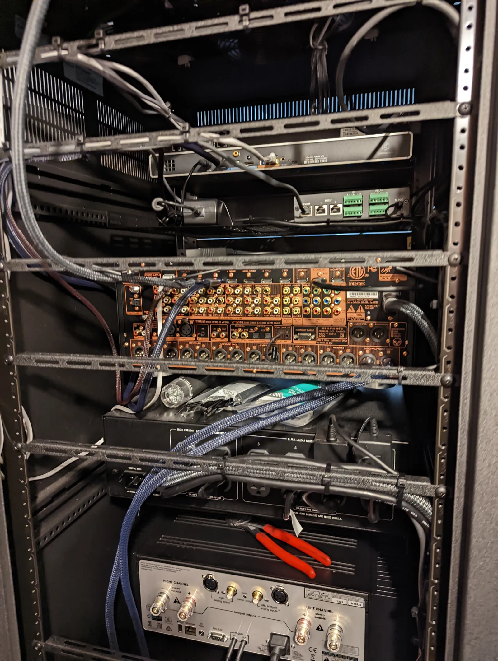 Rear of equipment rack mid-wiring showing dozens of labeled audio and video terminations